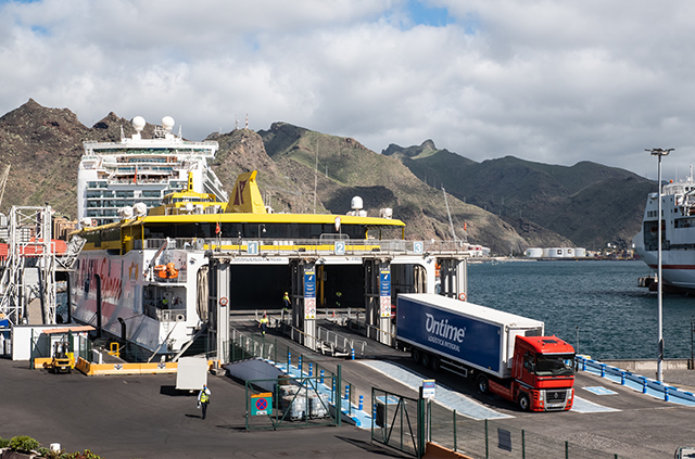 Marquesina y antiguo faro del puerto con ferry de transporte